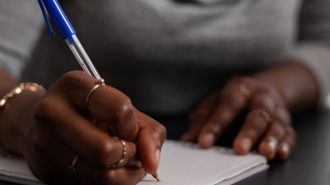 Close up of woman taking notes with pen on textbook